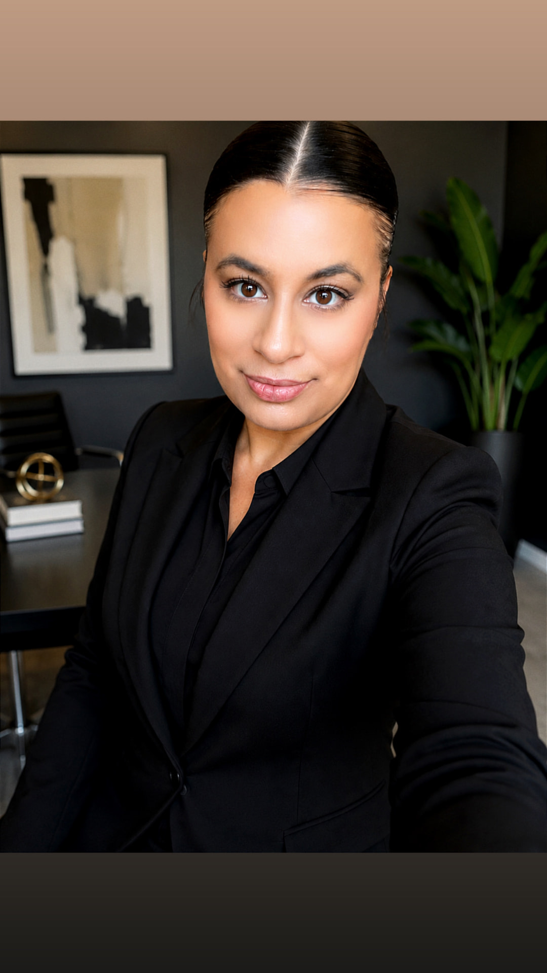 Founder and CEO of stay thirty8 in a black tailored blazer at her office desk